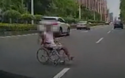 男子坐着轮椅在马路上碰瓷挡在车前不让离开